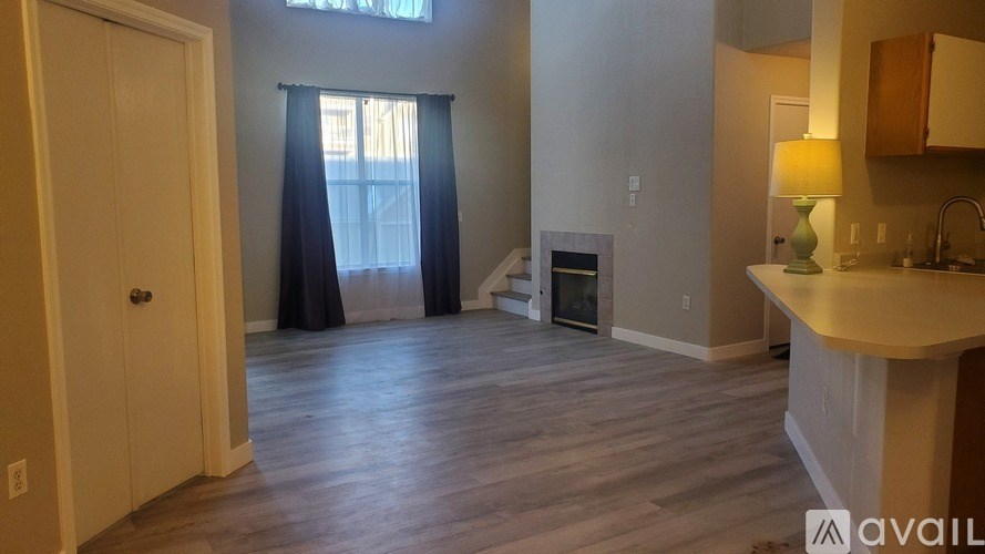 A large empty room with a window and a whiteboard on the wall.