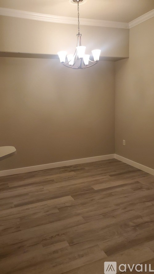 A room with wooden flooring and a chandelier hanging from the ceiling.