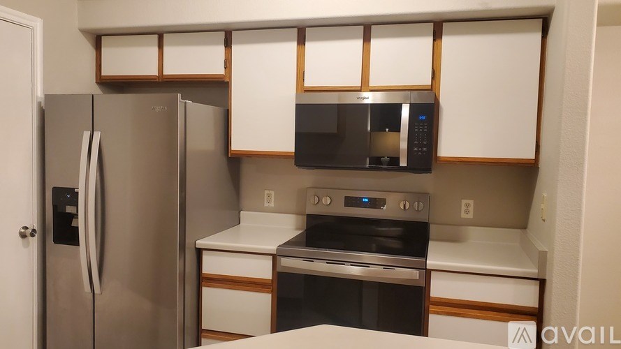 A kitchen with a stainless steel refrigerator, microwave, oven, and white countertops.
