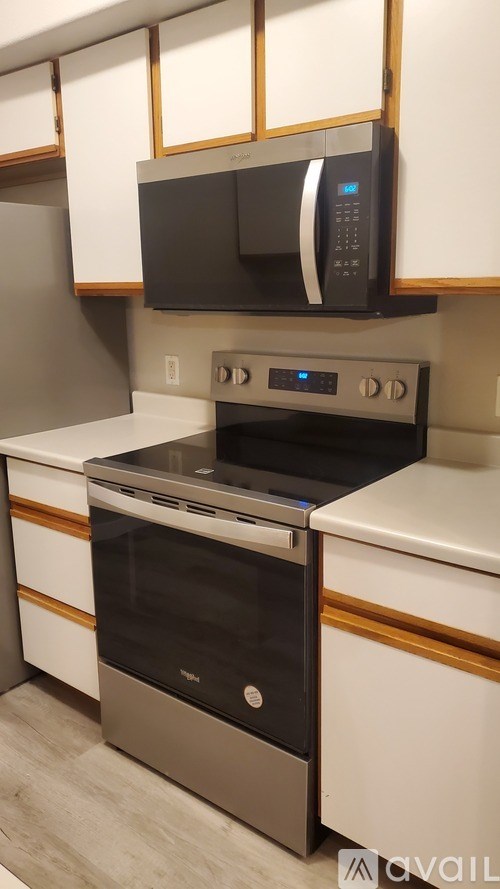A black microwave oven is mounted above a stainless steel oven in a kitchen.