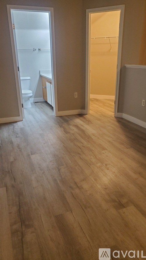 A room with wooden flooring and two open doors.