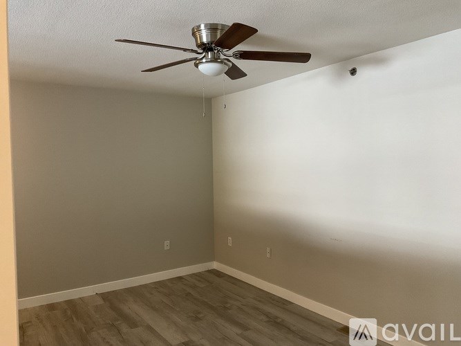 A room with a ceiling fan and wooden flooring.