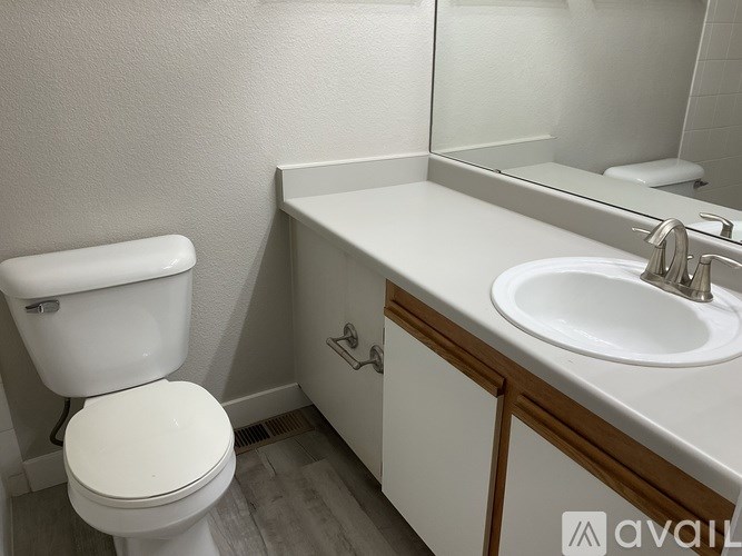 A white toilet sits next to a white sink in a small bathroom.