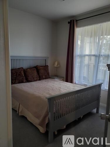 A bedroom with a bed, pillows, and a window with curtains.