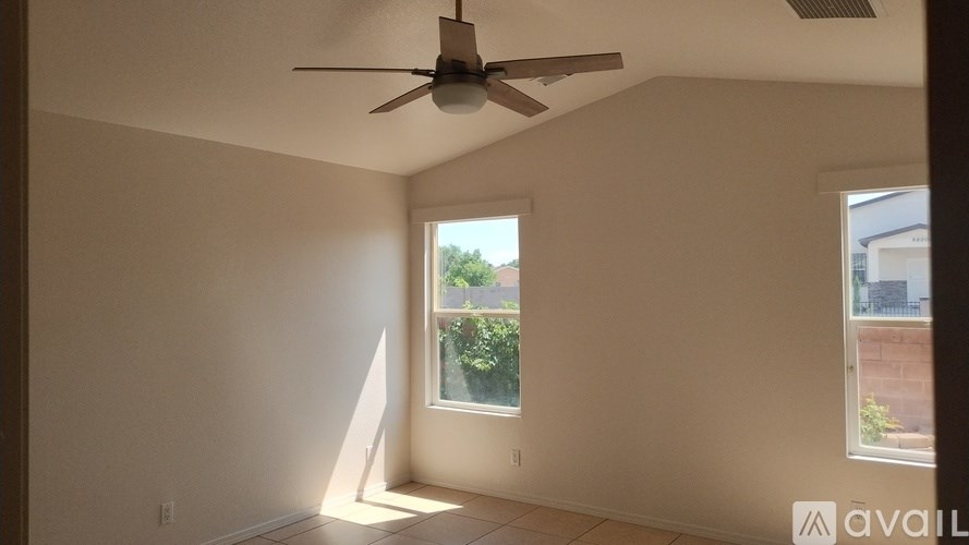 A room with a ceiling fan and two windows.