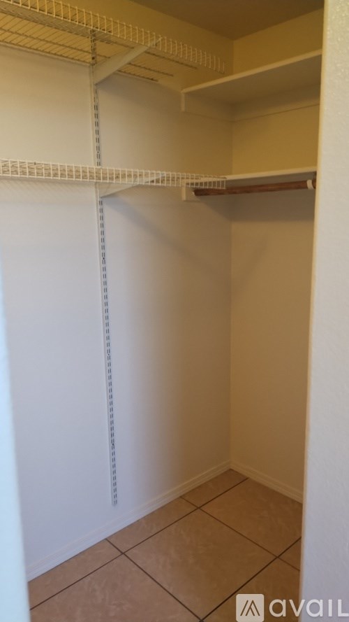 A white closet with shelves and a tiled floor.