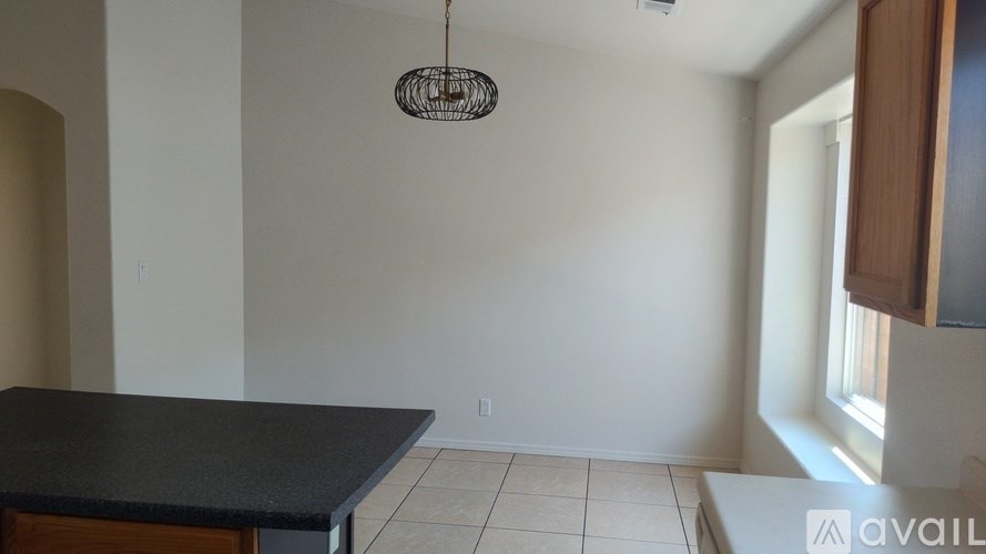 A room with a black countertop and a hanging light fixture.