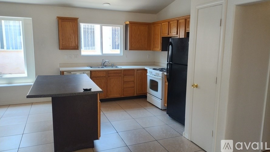 A kitchen with a black refrigerator and wooden cabinets.