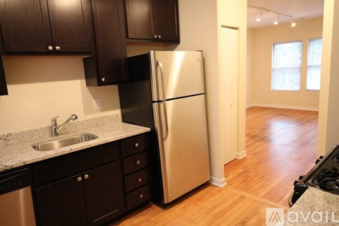 A kitchen with a black fridge and brown cabinets.