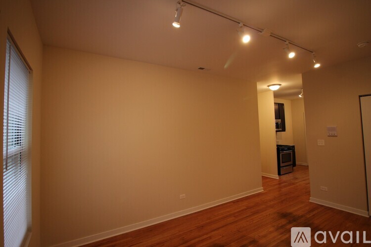 A room with wooden floors and a white wall with a door on the right side.