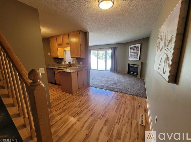 A living room with a staircase on the left and a kitchen area in the background.