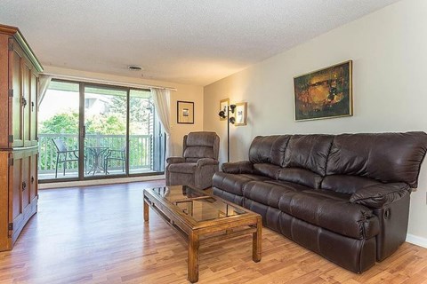 A living room with a black leather couch and a wooden coffee table.