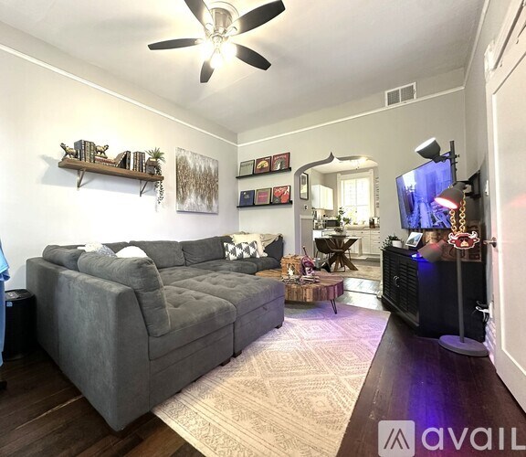 A living room with a grey couch and a ceiling fan.