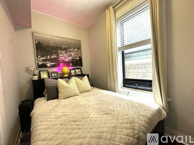 A bedroom with a large bed, a window with curtains, and a framed picture on the wall.