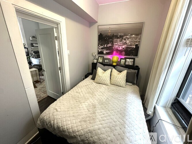 A bedroom with a bed, a dresser, and a framed picture on the wall.