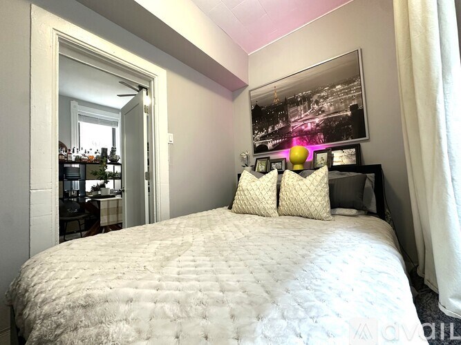 A bedroom with a large bed and a framed picture on the wall.