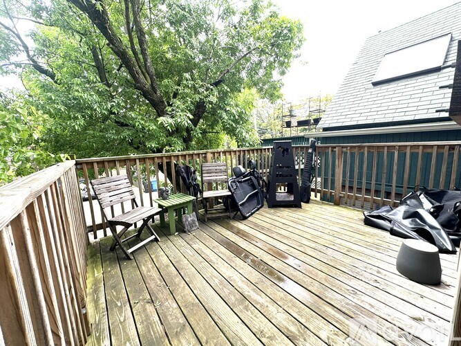 A wooden deck with a table and chairs and a grill.
