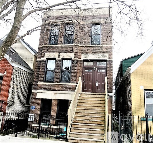 A brown building with a black gate in front.