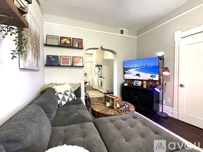 A living room with a grey couch and a television displaying a beach scene.