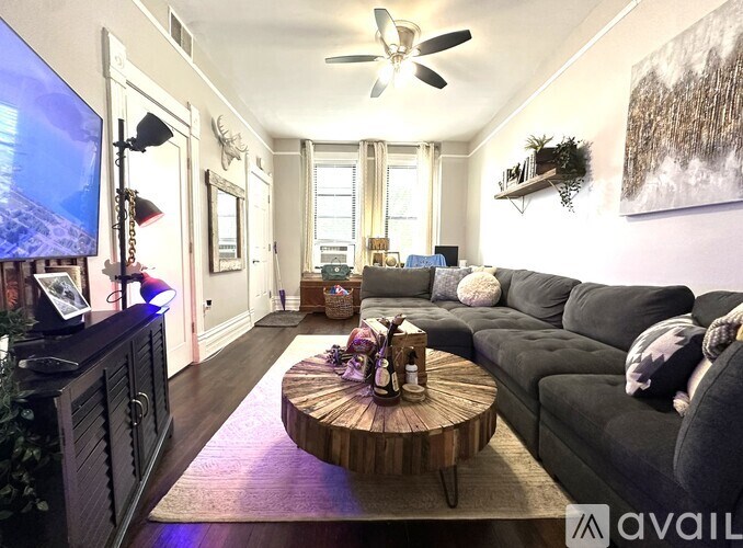 A living room with a grey couch, a wooden coffee table, and a flat screen TV mounted on the wall.