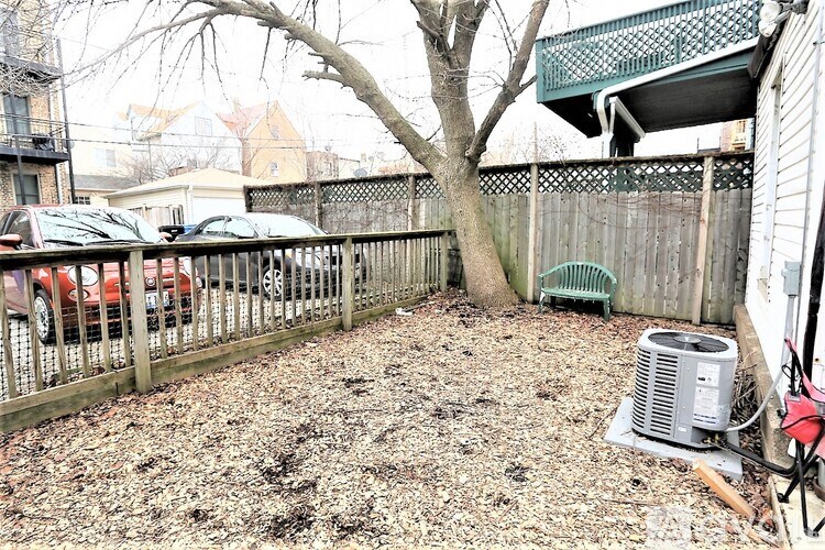 A backyard with a tree, a fence, and a carport.