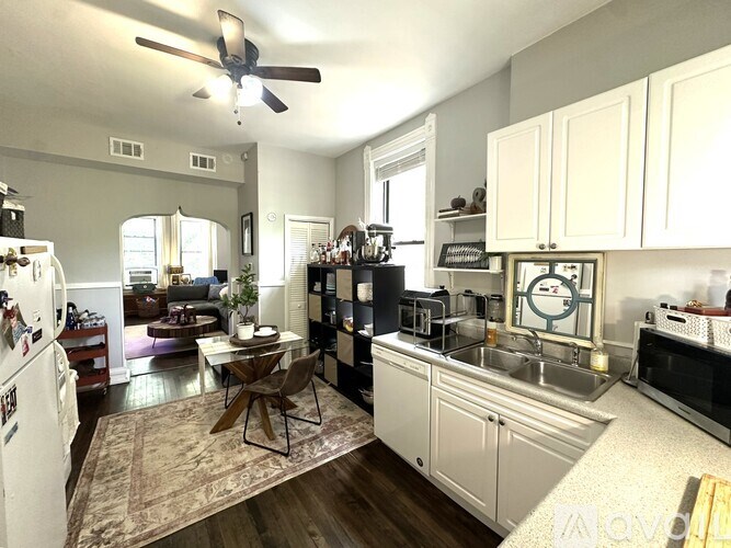 A kitchen with white cabinets and a black fridge.