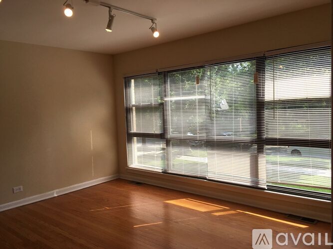 A room with wooden floors and a large window with blinds.