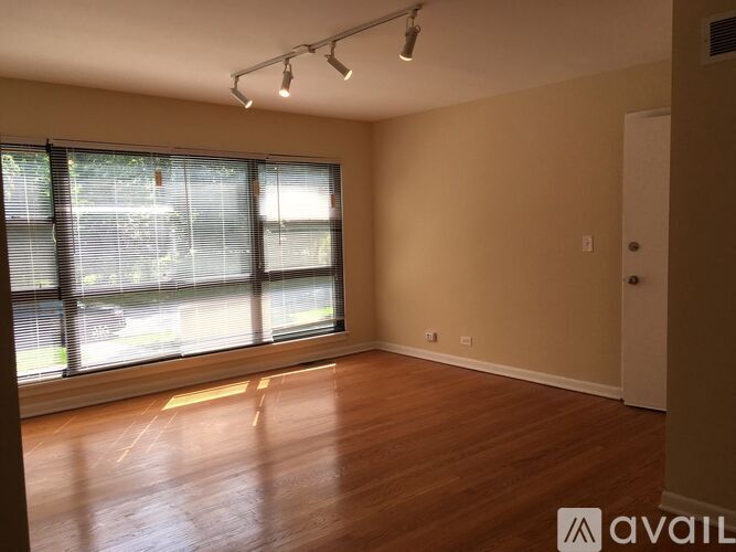A room with wooden floors and a large window with blinds.