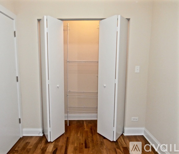 A white closet with shelves and a wooden floor.