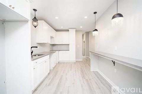 A spacious kitchen with white cabinets and a wooden floor.