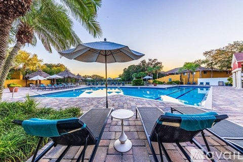 A pool area with two lounge chairs and an umbrella.
