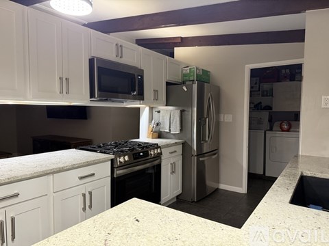 A kitchen with white cabinets and a stainless steel refrigerator.
