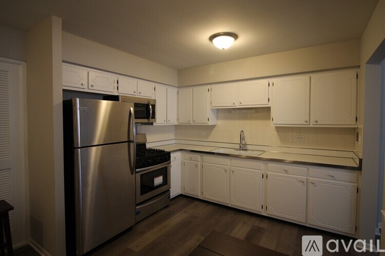 A kitchen with white cabinets and a stainless steel refrigerator.