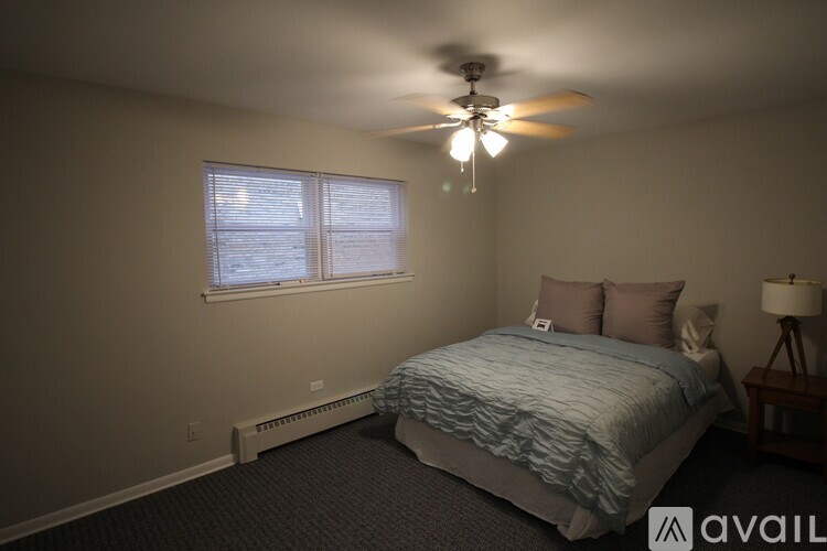 A bedroom with a bed, a ceiling fan, and a window.
