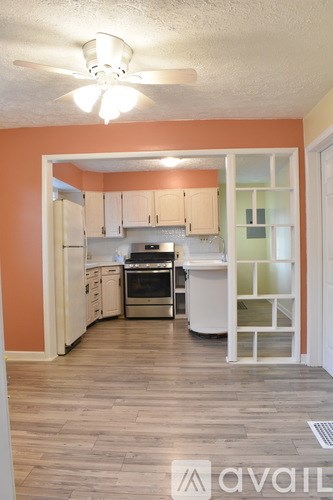 A kitchen with orange walls and white cabinets.