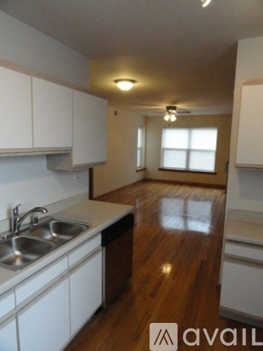 A kitchen with white cabinets and a wooden floor.