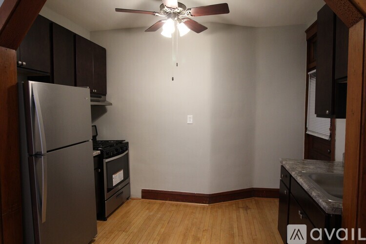 A kitchen with a refrigerator, oven, and a ceiling fan.
