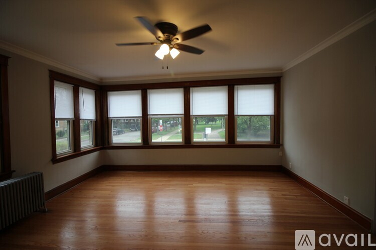 A room with a ceiling fan and large windows.