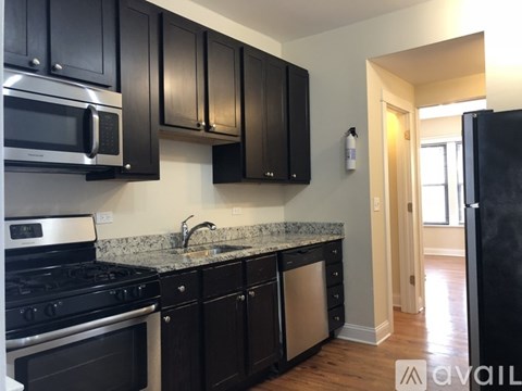 A kitchen with black cabinets and a granite countertop.