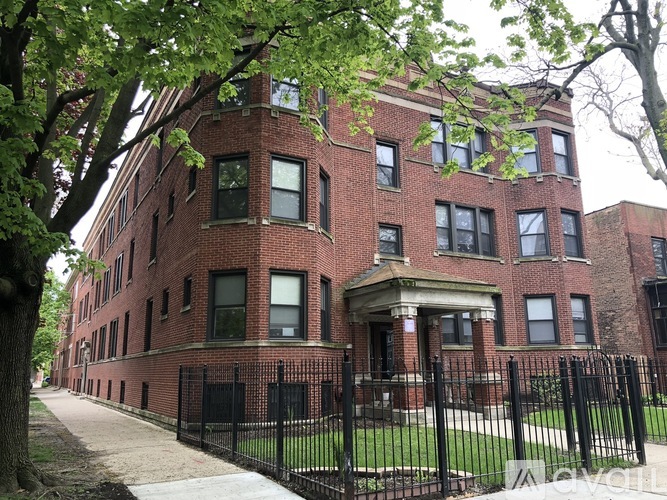 A red brick building with a black fence in front.