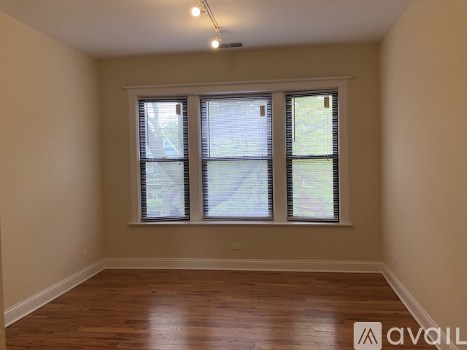 A room with wooden floors and a large window with blinds.
