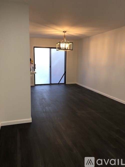 A room with dark wood flooring and a chandelier hanging from the ceiling.