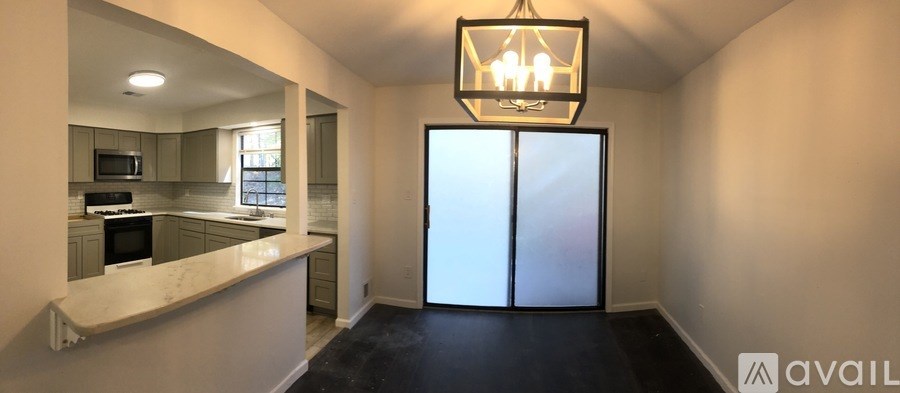 A kitchen with a white counter top and a chandelier hanging from the ceiling.