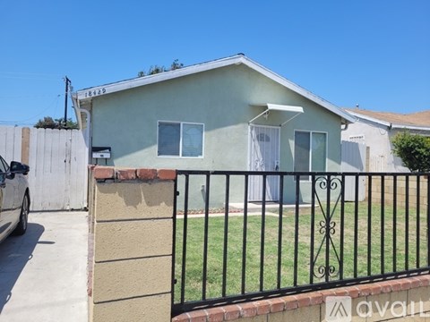 A house with a fence and a car parked in front.