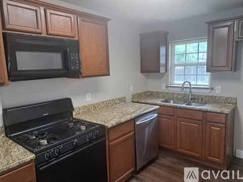 A kitchen with a black stove and wooden cabinets.