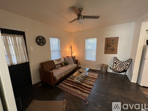 A living room with a brown couch and a rug.