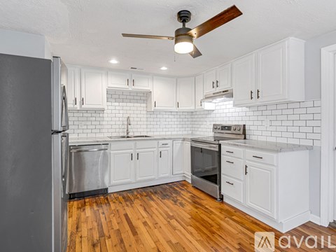 A kitchen with white cabinets and a wooden floor.