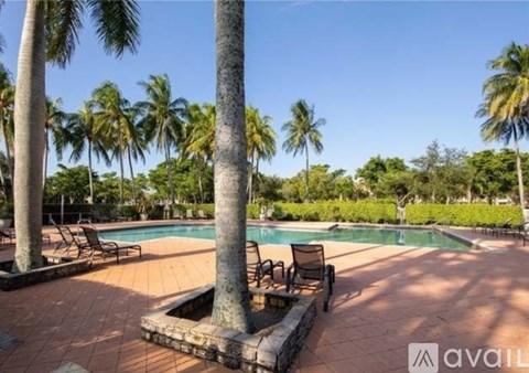 A pool surrounded by palm trees and lounge chairs.