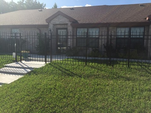 A house with a black fence and green grass in front.