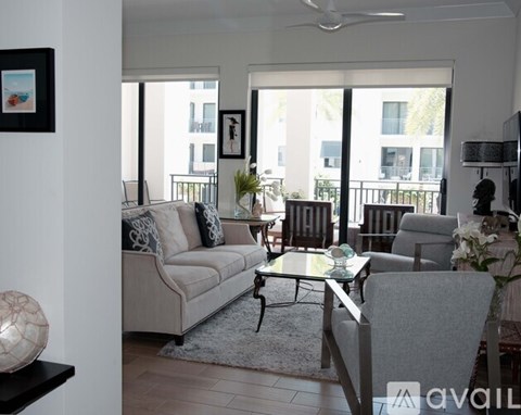 A living room with a couch, chairs, and a table with a vase of flowers on it.